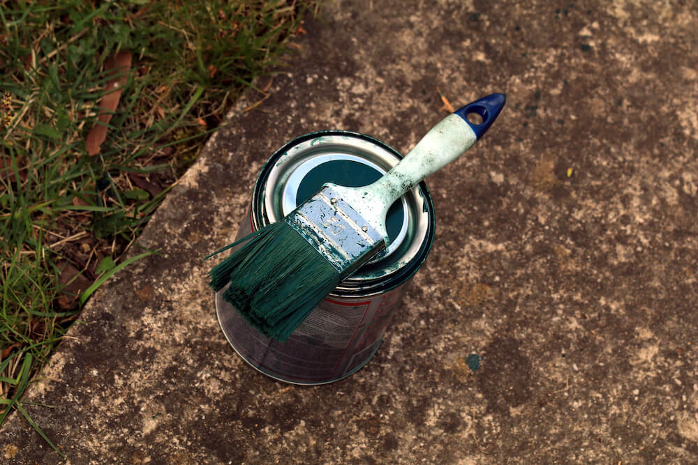 Tin of green exterior paint and a paint brush